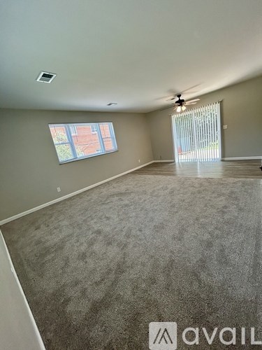 A room with a carpeted floor and a window with blinds.
