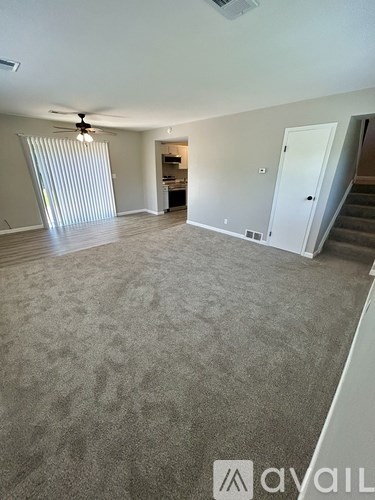 A spacious living room with a carpeted floor and a ceiling fan.