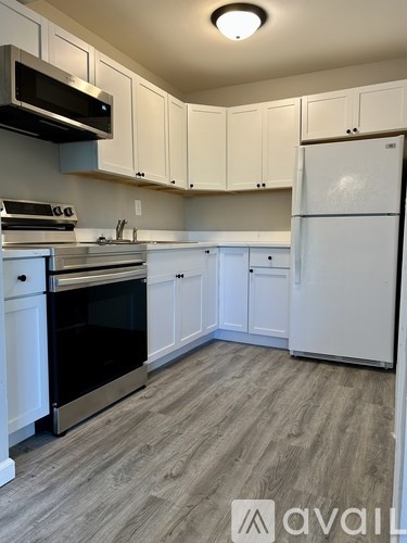 A kitchen with white cabinets and a wooden floor.