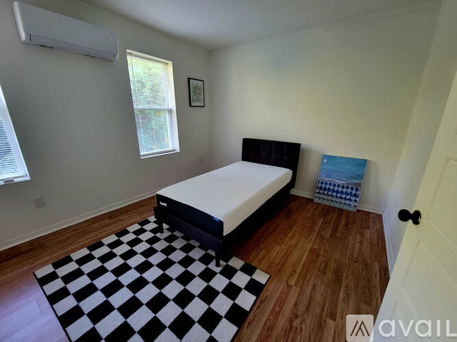 A bedroom with a black and white checkered rug and a black bed.