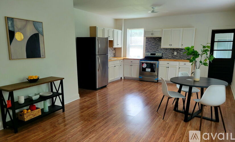A kitchen with a black fridge and wooden floors.