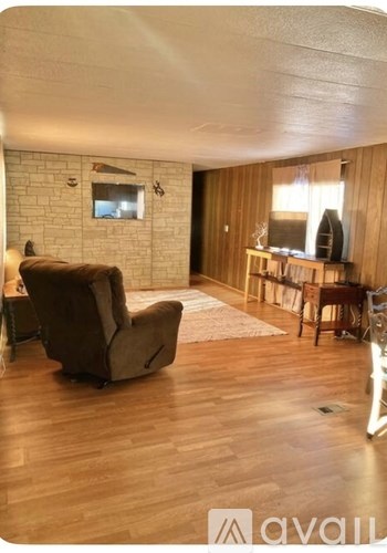 A living room with a brown chair and a white brick wall.