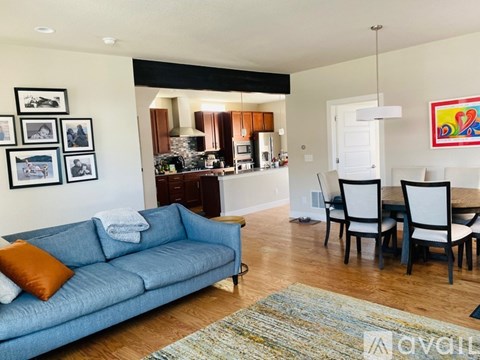 A living room with a blue couch and a dining table with chairs.