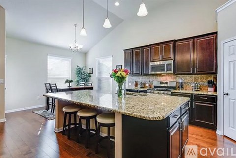 A kitchen with dark wood cabinets and a granite countertop.