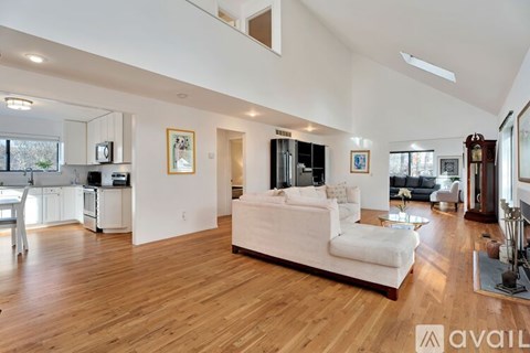 A spacious living room with a white sofa and wooden flooring.