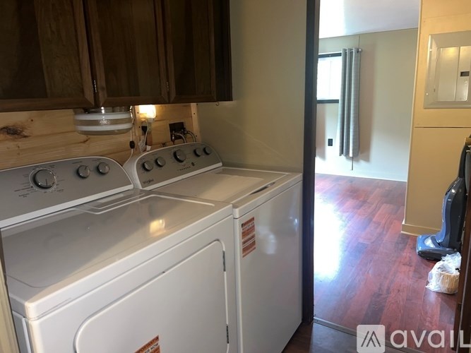 A room with wooden floors and two windows with curtains.