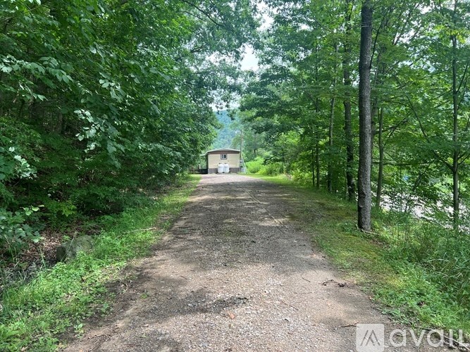 A wooden deck with a metal railing and a view of a pathway through the trees.