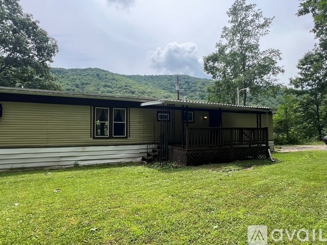 A grassy area with a dirt path leading to a small building and a shed.