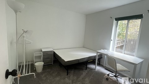 A room with a bed, desk, chair, and a radiator.