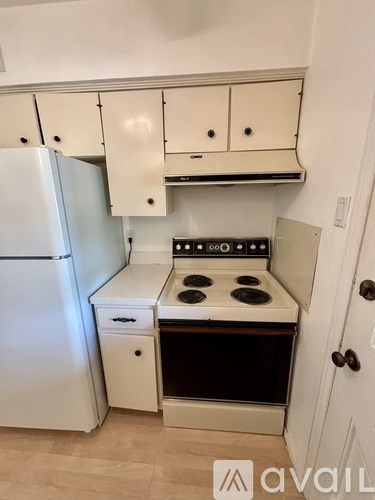 A kitchen with a white refrigerator, white cabinets, and a white stove top oven.