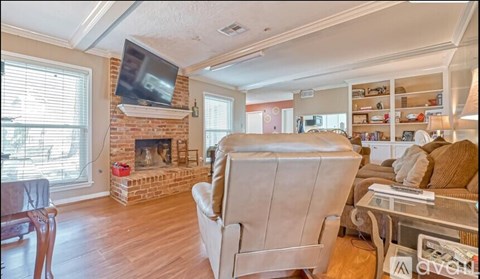 A living room with a fireplace and a television mounted above it.