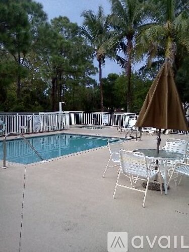 A pool area with chairs and an umbrella.