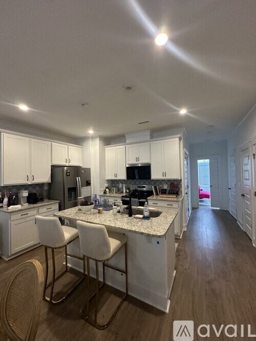 A kitchen with white cabinets and a central island with two chairs.