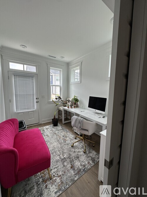A room with a red chair and a desk with a computer.