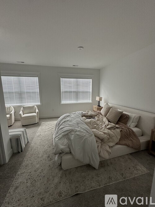 A bedroom with a large bed and two chairs.