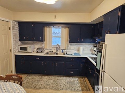 A kitchen with dark blue cabinets and a white refrigerator.
