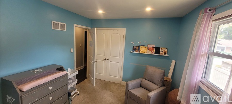 A baby crib sits in a room with blue walls.