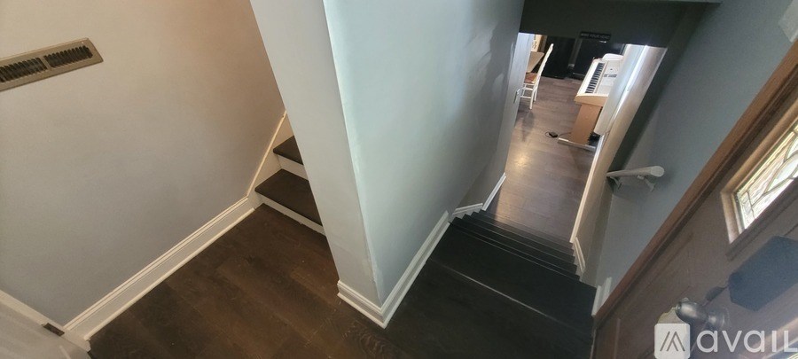 A stairway with a black carpeted runner and white walls.