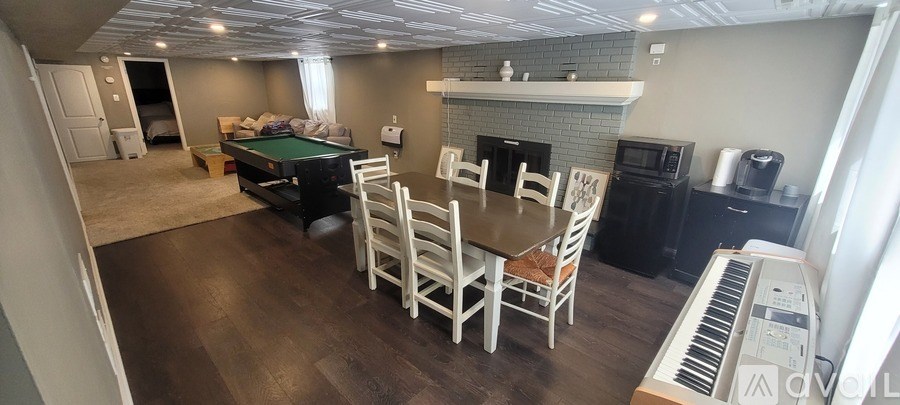 A living room with a pool table and a piano.