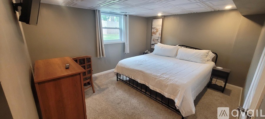 A bedroom with a bed, nightstand, and a window.