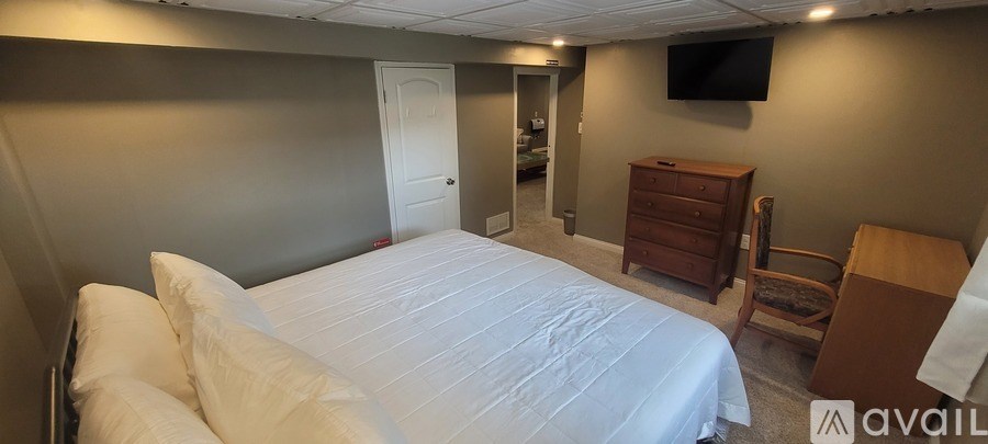 A bedroom with a large bed and a TV mounted on the wall.