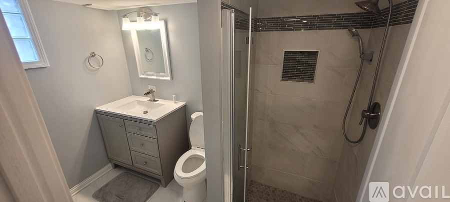 A bathroom with a toilet, sink, mirror, and shower.
