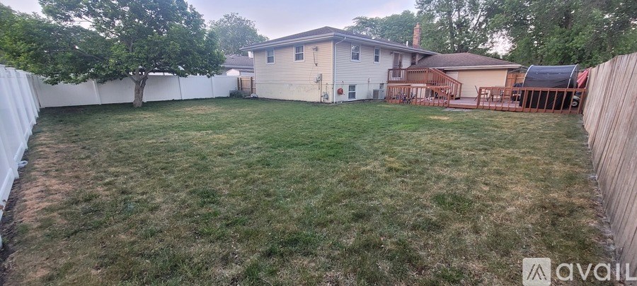 A backyard with a white fence and a house in the background.