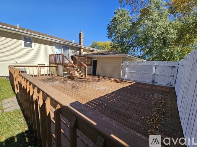 A wooden deck with a white fence and a house in the background.