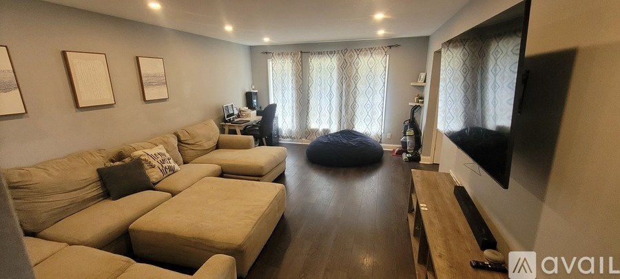 A living room with a large couch and a television on the wall.