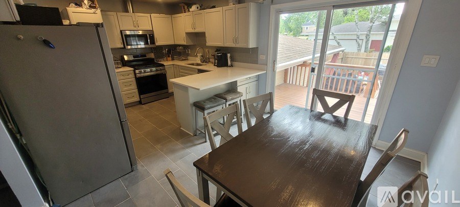 A kitchen with a table and chairs in front of a sliding glass door.