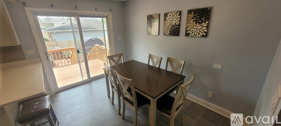 A dining room with a table and chairs and a balcony with a view of the water.
