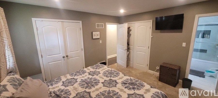 A bedroom with a large bed and a flat screen TV mounted on the wall.