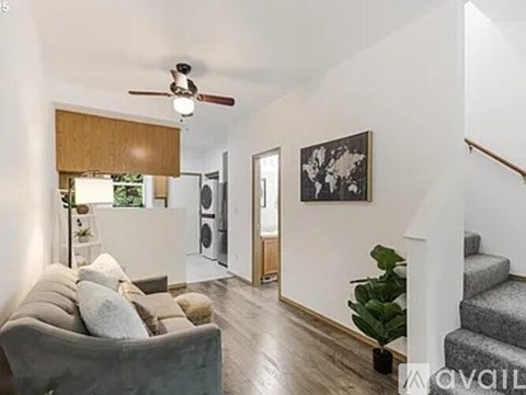A living room with a grey couch and a staircase.