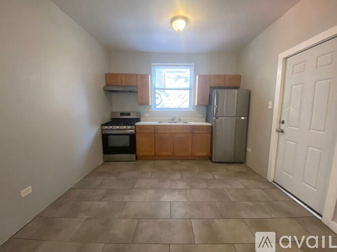 A kitchen with a refrigerator, oven, and sink.