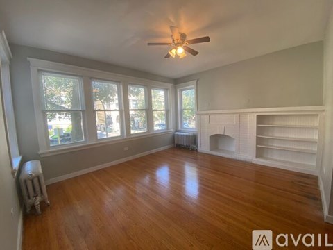 A spacious room with wooden floors and a ceiling fan.
