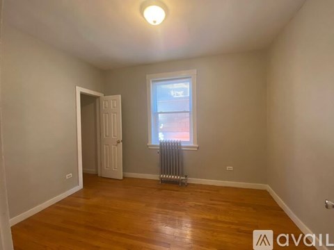 A room with wooden floors and a window with a view of a building outside.