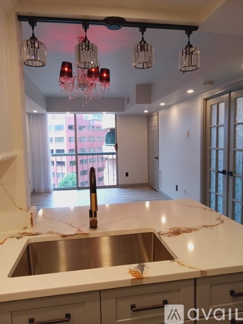 A kitchen with a marble counter top and a stainless steel sink.