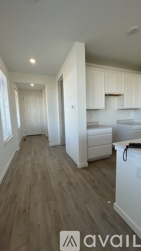 A kitchen with white cabinets and a wooden floor.