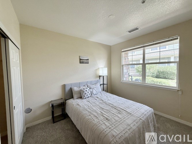 A bedroom with a large bed and a window overlooking a green area.