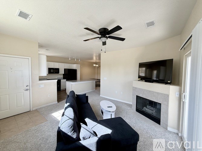 A living room with a black couch and a fireplace.