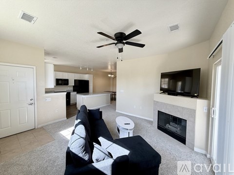 A living room with a black couch and a fireplace.