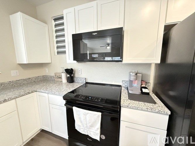 A black microwave is mounted above a black oven in a kitchen.