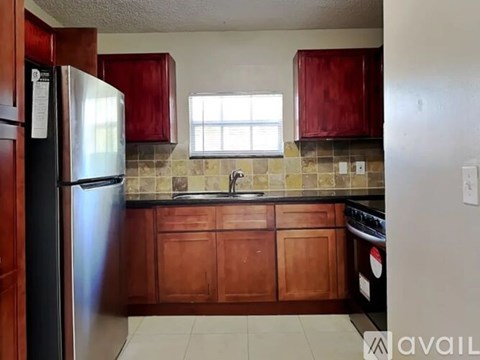 A kitchen with wooden cabinets and a stainless steel refrigerator.