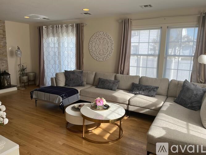 A living room with a large sectional sofa, a coffee table, and a window with curtains.