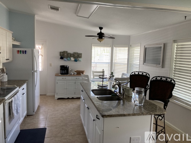 A kitchen with a refrigerator, sink, and chairs.