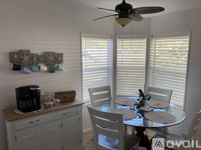 A dining room with a glass table and white chairs.