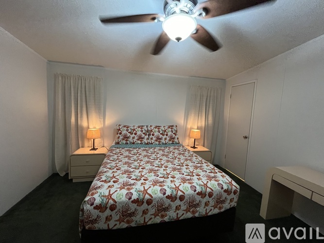 A bedroom with a bed, nightstands, and a ceiling fan.