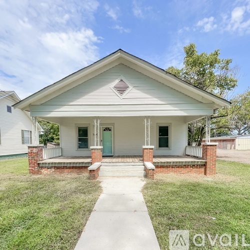 A small white house with a green door and a brick pillar.