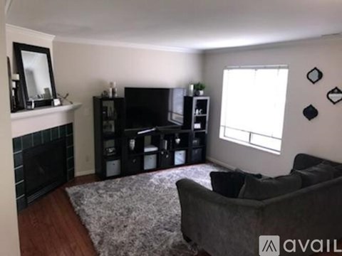 A living room with a grey couch and a fireplace.