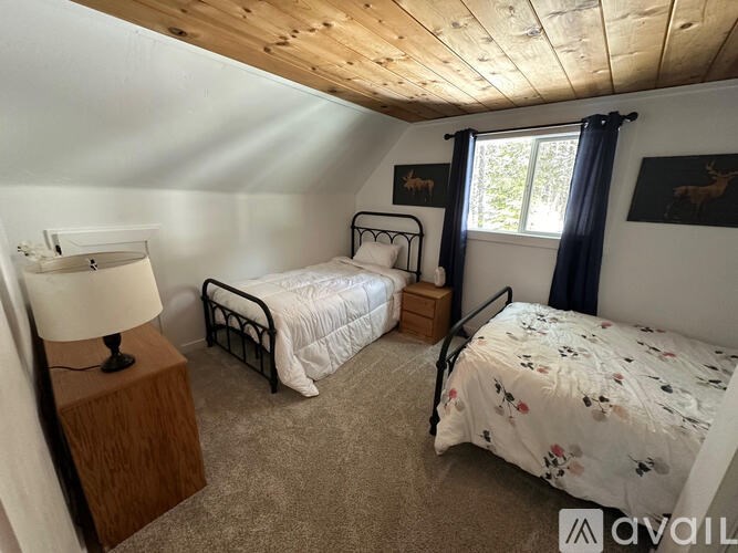 A bedroom with two beds, one with a white comforter and the other with a floral comforter.